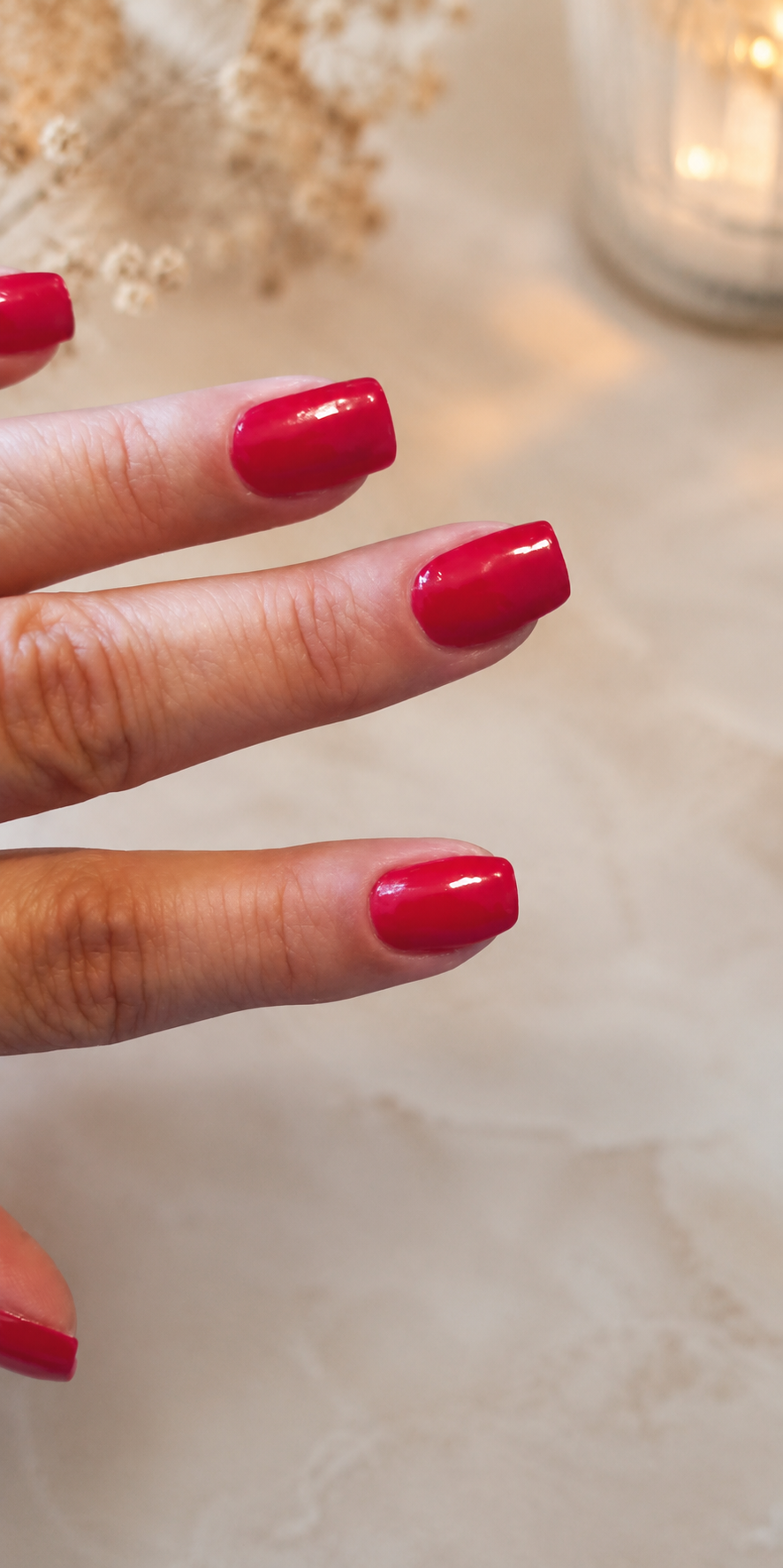 Glossy deep red manicure on a soft beige background